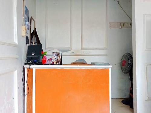 un bancone arancione in una cucina con armadi bianchi di Reddoorz @ Kanaka GuestHouse a Bengkulu