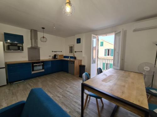 une cuisine et une salle à manger avec une table en bois et des chaises bleues dans l'établissement Appartement rénové indépendant avec garage au centre du village, à Saint-Florent