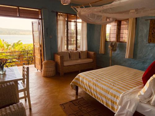 a bedroom with a bed and a chair and a window at HomeOnTheNile Lake view double in Jinja