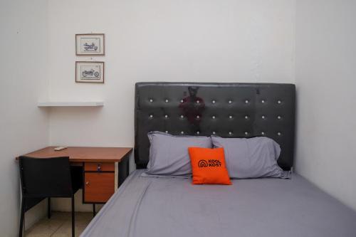 a bed with an orange pillow on it next to a desk at KoolKost Syariah near Luwes Gentan Park (Minimum Stay 30 Nights) in Sukoharjo