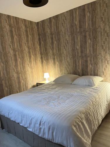 a bedroom with a large bed with a wooden wall at Le troubadour in La Roche-sur-Foron