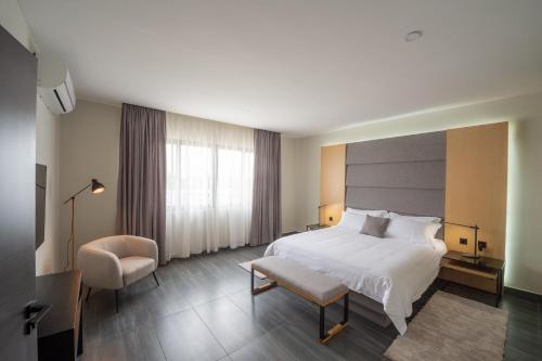 une chambre d'hôtel avec un lit et une chaise dans l'établissement Agora Apartments, à Lusaka