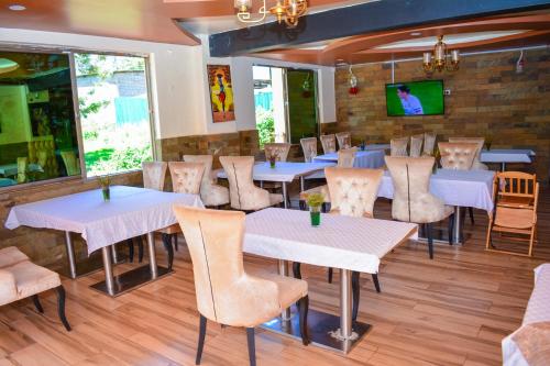 um restaurante com mesas e cadeiras e uma parede de tijolos em Omega Gardens Hotel em Karatina