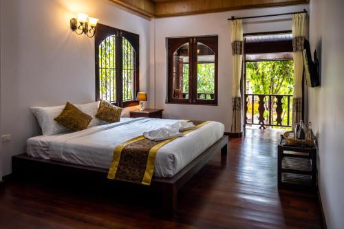 a bedroom with a large bed and two windows at Villa Mira Heritage in Luang Prabang