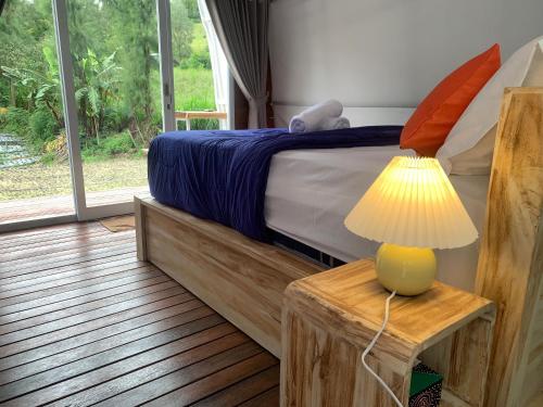 a bedroom with a bed with a lamp on a table at Volcano rim Glamping Kintamani in Kubupenlokan