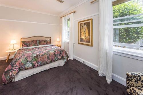 a bedroom with a bed and a large window at Centennial Cottage 2 - Botanica in Bowral