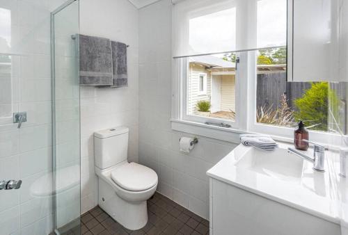 a bathroom with a toilet and a sink and a window at Centennial Cottage 2 - Botanica in Bowral