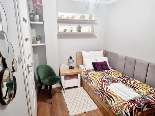 niewielka sypialnia z łóżkiem i zielonym krzesłem w obiekcie Promenada Room Ełk w mieście Ełk