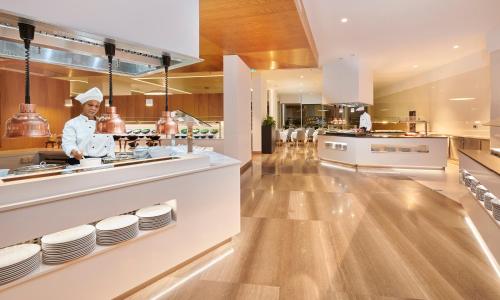 a chef preparing food in a restaurant kitchen at Hipotels Playa de Palma Palace&Spa in Playa de Palma