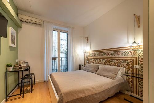 a bedroom with a bed and a desk and a window at Casa Abbanniata a Ballaro' in Palermo