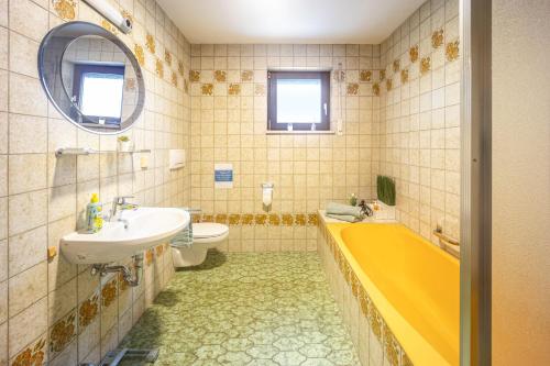 een badkamer met een geel bad en een wastafel bij Erkheim in Erkheim