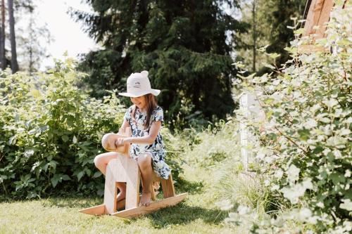 a little girl sitting on a wooden toy horse at Guesthouse Torppa in Korkeakoski
