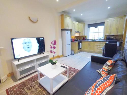 a living room with a couch and a flat screen tv at Flat 2, 6 Tauton Mews in Marylebone in London