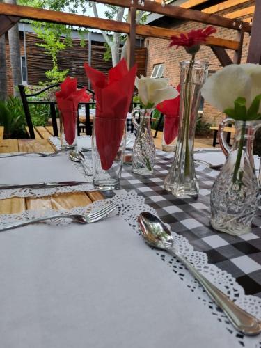 una mesa con jarrones y cubiertos sobre un mantel a cuadros en Gorgeous Gecko Guesthouse, en Modimolle