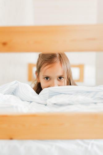 a young girl laying in bed looking through a book at Guesthouse Torppa in Korkeakoski
