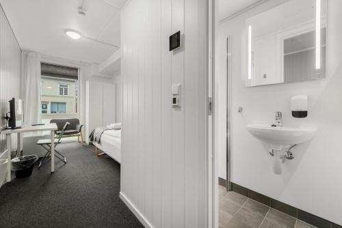a bathroom with a sink and a bedroom with a bed at Norpark Romutleie in Orkanger
