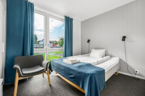 een slaapkamer met een bed, een stoel en een raam bij Norpark Romutleie in Orkanger