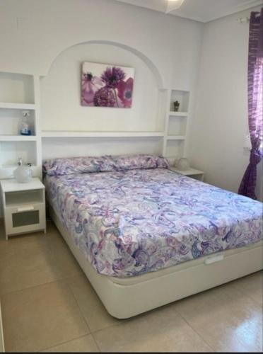 a bedroom with a bed with a purple comforter at Playa Flamenca 151 in Playa Flamenca