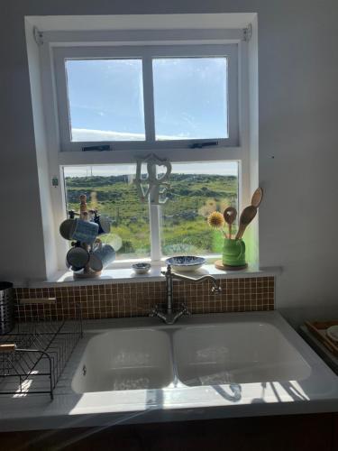 a kitchen sink in front of a window with a view at Pink Cottage in Ballyconneely