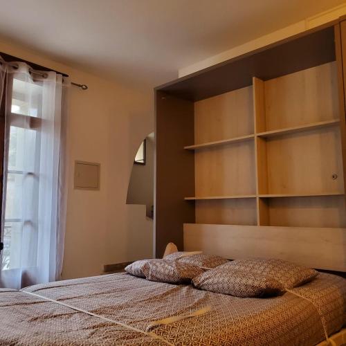 uma cama com duas almofadas num quarto em MACLENFA: charmant studio au cœur de l’Herault. em Saint-Guilhem-le-Désert