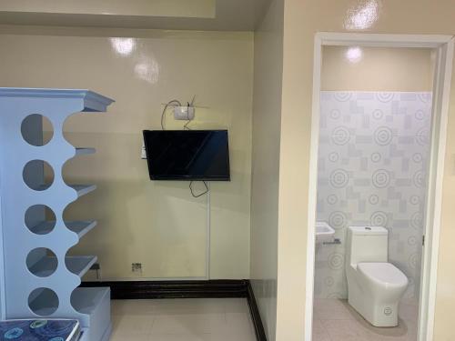 a bathroom with a toilet and a tv on the wall at Suncrest Inn in Butuan
