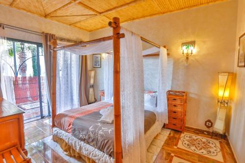 a bedroom with a canopy bed and a window at Maison Kasba Bonheur & Bien etre Emma & Gilles in Essaouira