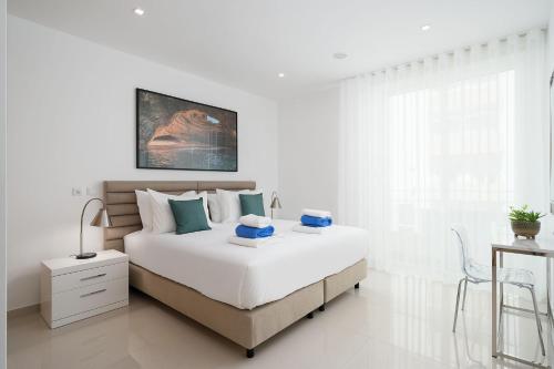 um quarto branco com uma cama grande e uma secretária em Marina Pearl Deluxe Lagos Apartment by Ideal Homes em Lagos