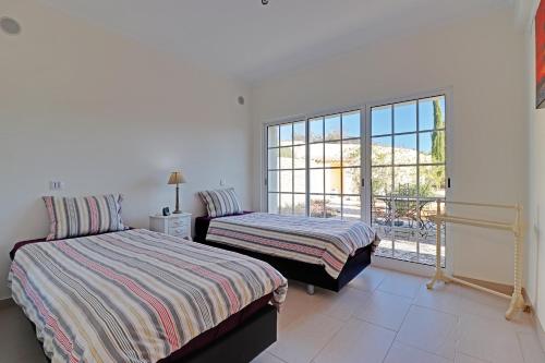 1 dormitorio con 2 camas y balcón en Casa de Apra by Portucasa en Loulé