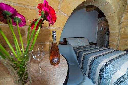 a table with a bottle and a vase with flowers at Valletta Old Well Apartments in Valletta