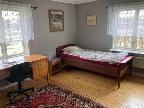 um quarto com uma cama, uma secretária e janelas em Setons Stuga em Lindesberg