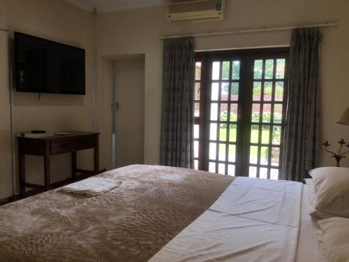a bedroom with a bed and a tv and a window at A boutique lodge situated in a serene environment - 2030 in Harare