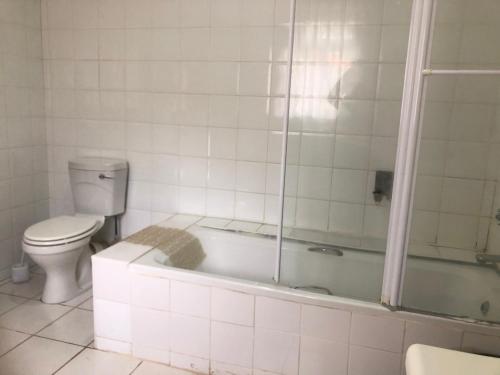 a bathroom with a toilet and a bath tub at A boutique lodge situated in a serene environment - 2030 in Harare