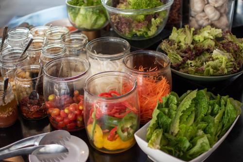 a table with many different types of vegetables in jars at Hotel Clover Asoke - SHA Extra Plus in Bangkok