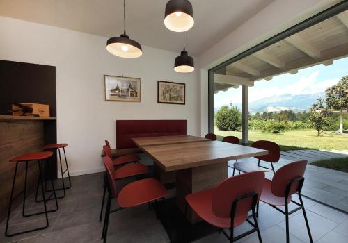 uma sala de jantar com uma mesa de madeira e cadeiras vermelhas em Agritur Ponte Alto em Trento