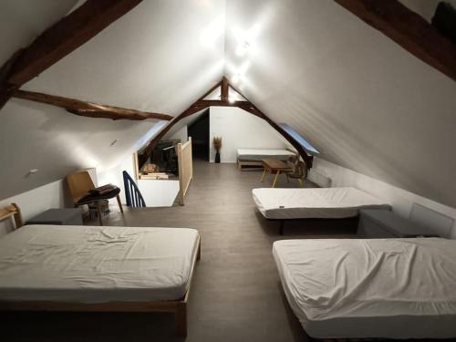 pokój na poddaszu z dwoma łóżkami i stołem w obiekcie Grande, belle maison de ville idéale 24 h du Mans w mieście Vaas