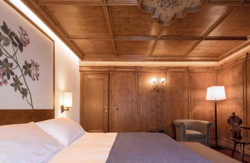 una camera con letto e soffitto in legno di Faloria Mountain Spa Resort a Cortina dʼAmpezzo