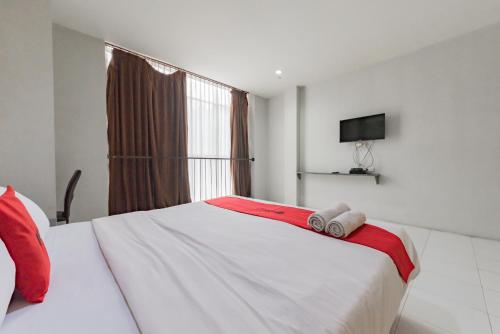 a bedroom with a large white bed with a red blanket at RedDoorz @ Pelajar Pejuang 3 in Bandung