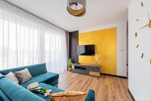 Una sala de estar con un sofá azul y un televisor. en Horyzont Apartamenty -Bałtycka2 - SAUNA & FITNESS - ŚNIADANIA, en Kołobrzeg