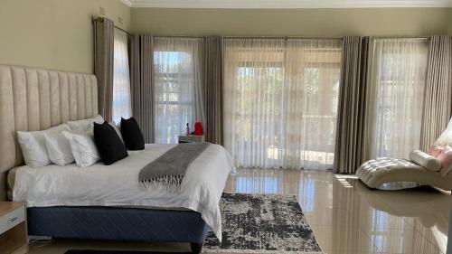 a bedroom with a large bed with windows and a rug at Commodious and Contemporary double home - 2042 in Bulawayo