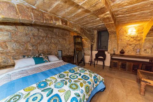 1 dormitorio con cama y pared de piedra en Valletta Traditional Townhouse en La Valeta