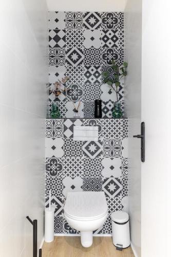 La salle de bains est pourvue de toilettes et de carrelage noir et blanc. dans l'établissement HSH Batignolles Sauffroy Charming Apartment 8P, à Paris
