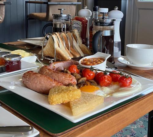 Weobley的住宿－Marshpools Bed & Breakfast - Licensed near Weobley village，餐桌上放着一盘带香肠和西红柿的食物