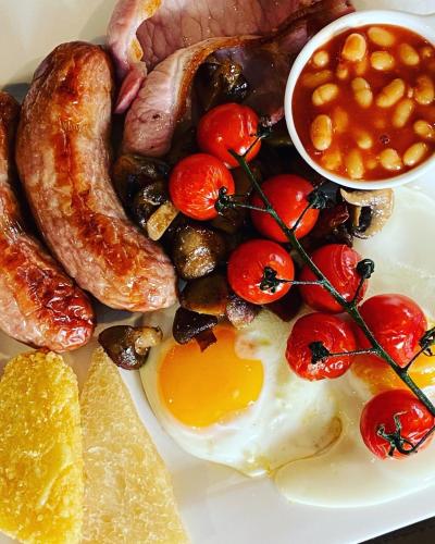 a plate of breakfast food with eggs sausage and beans at Marshpools Bed & Breakfast - Licensed near Weobley village in Weobley