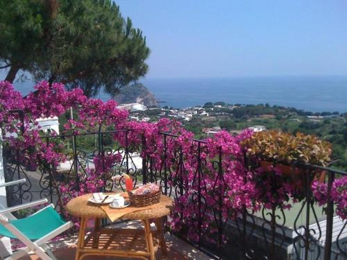 a table and chairs on a balcony with purple flowers at Hotel Bellavista Ischia in Ischia