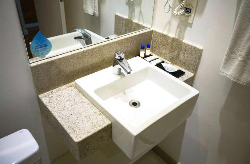 a bathroom with a white sink and a mirror at Quarto plus no Linhares Design Hotel ES in Linhares