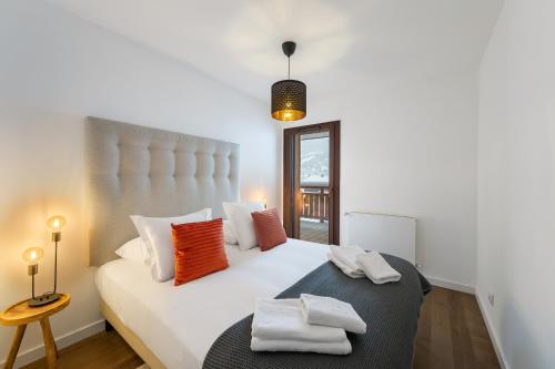 a bedroom with a large white bed with orange pillows at Alpujarra - Apt 304 - BO Immobilier - Châtel - remises sur les forfaits de skis Châtel ou Portes du soleil in Châtel