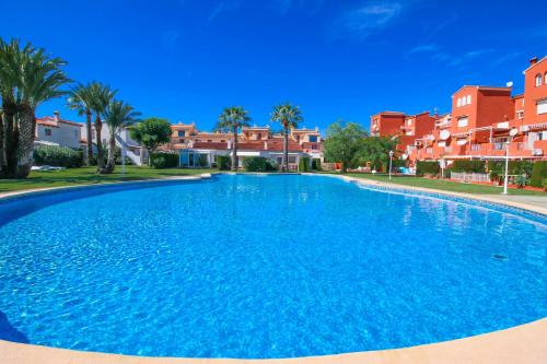 una gran piscina azul con palmeras y casas en Residencial El Cortijo by CARLOSFERIEN, en Denia