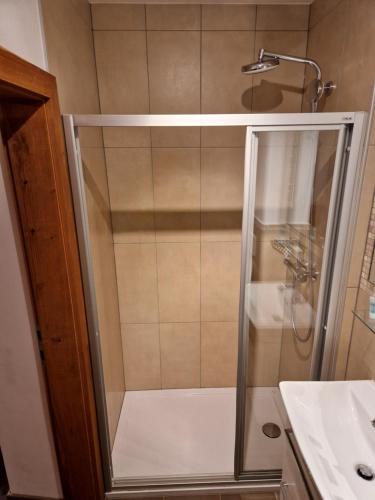 a shower with a glass door next to a sink at Gasthof Post in Mittersill