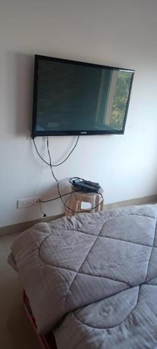 a flat screen tv hanging on a wall above a bed at URBAN NEST's BY VEGA SPACES in Belgaum