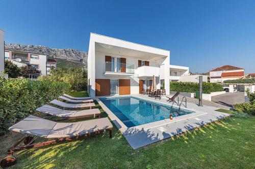 una casa con piscina e alcune sedie a sdraio di Luxury Villa Tina Moseni with private heated pool a Kaštela (Castelli)